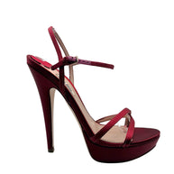 Side profile of a Miu Miu burgundy satin platform sandal with high stiletto heel, open toe, crossover straps and adjustable ankle buckle.