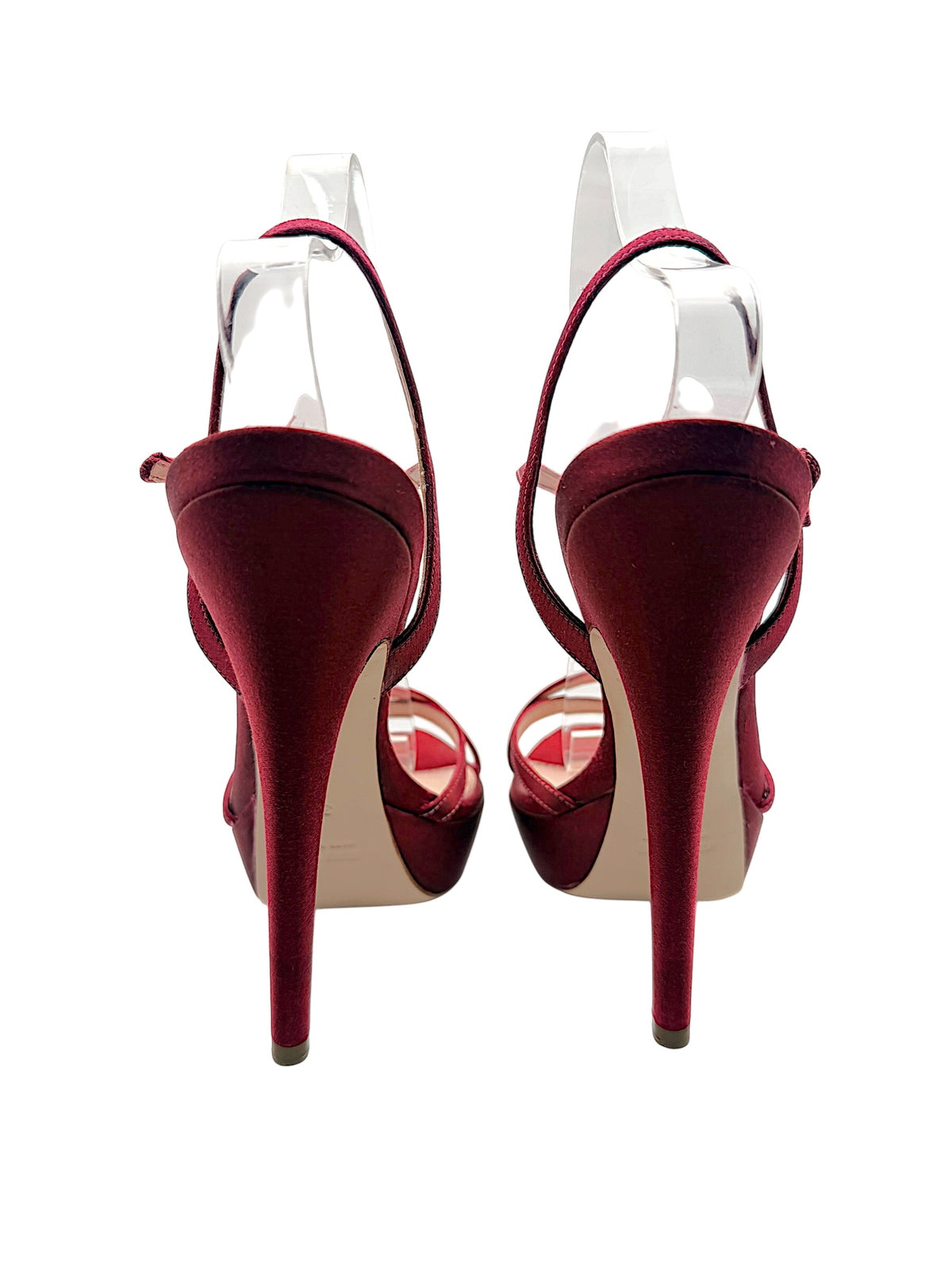 Rear view of Miu Miu burgundy satin platform heels showing tall satin-covered stilettos, heel tips and slender ankle straps.
