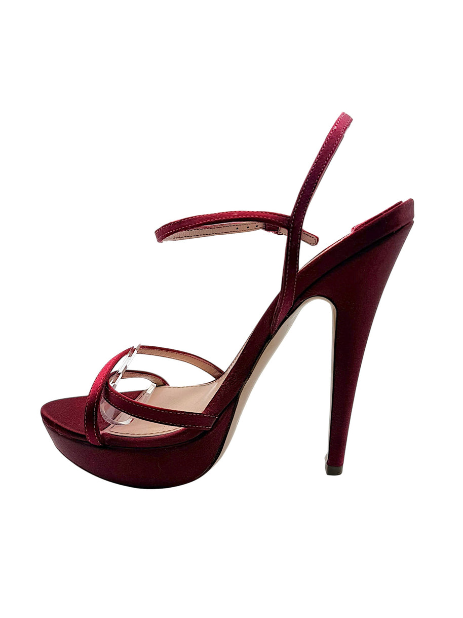 Opposite side view of a Miu Miu burgundy satin stiletto sandal highlighting its curved arch, raised platform and delicate ankle strap.