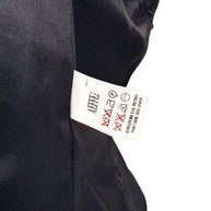 Interior care label of Moschino black tailored peplum jacket showing international garment care symbols, professional cleaning instructions and black lining.