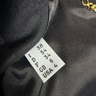 Close-up of Moschino black peplum jacket size label showing Italian 38, French 34, German 34, UK 6 and USA 4 sizing against the black lining.
