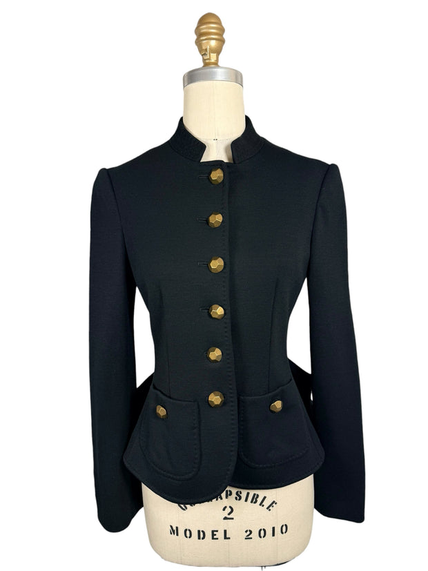 Front view of Moschino black structured jacket with six faceted gold-tone buttons, a fitted waist, stand collar and two rounded patch pockets.