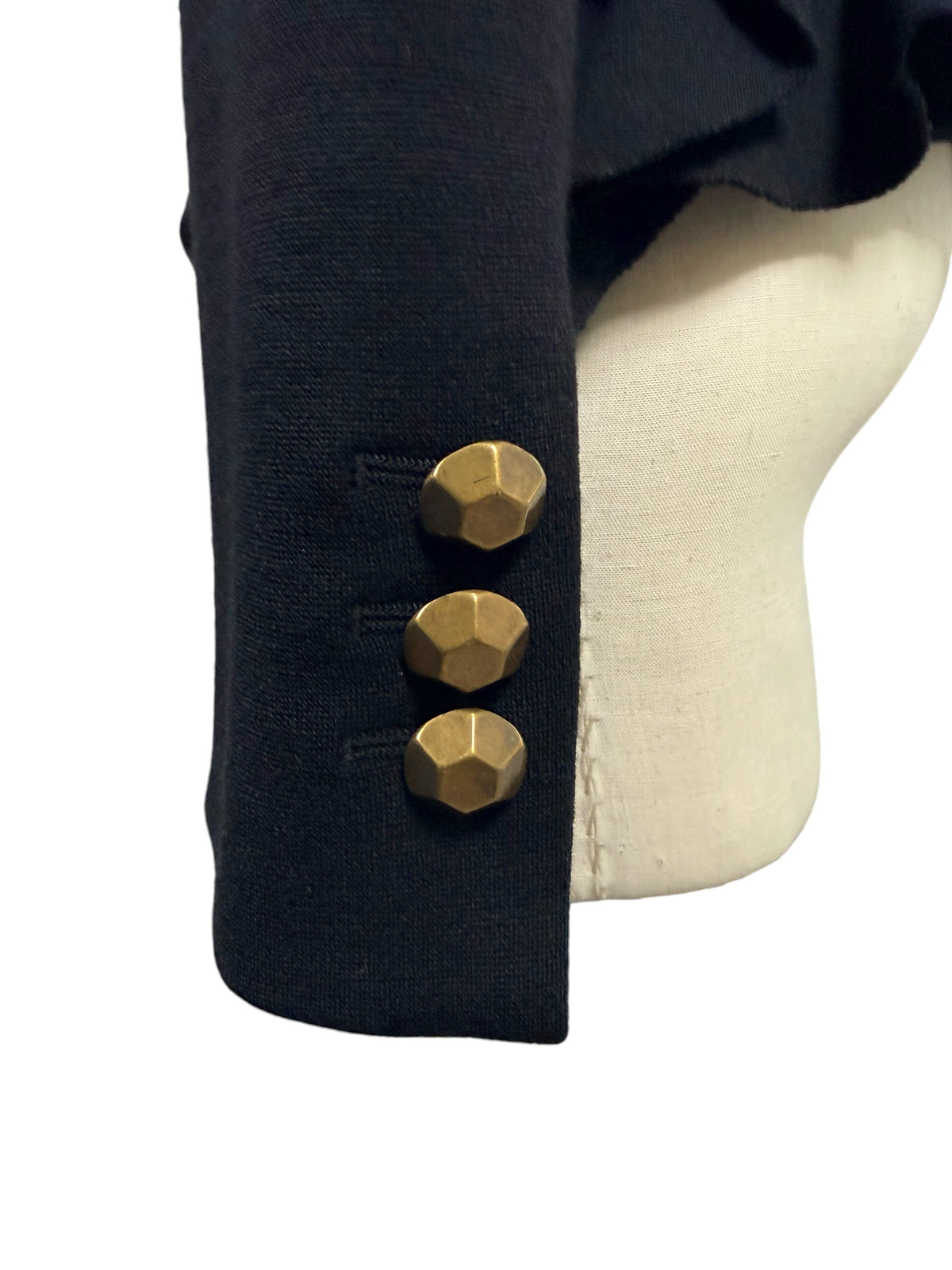 Close-up of Moschino black jacket sleeve cuff featuring three geometric faceted gold-tone buttons and neatly finished black fabric.