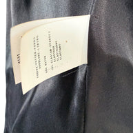 Close-up of Moschino black jacket composition label showing 85% rayon and 15% elastane-spandex, with the smooth black interior lining visible.