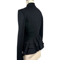 Three-quarter rear view of Moschino black tailored jacket highlighting the sculptural layered ruffle peplum, contoured back seams and gold-button cuff.