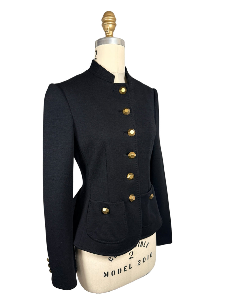 Three-quarter front view of Moschino black Italian tailored jacket highlighting its sculpted waist, gold-tone button closure and rounded front patch pocket.