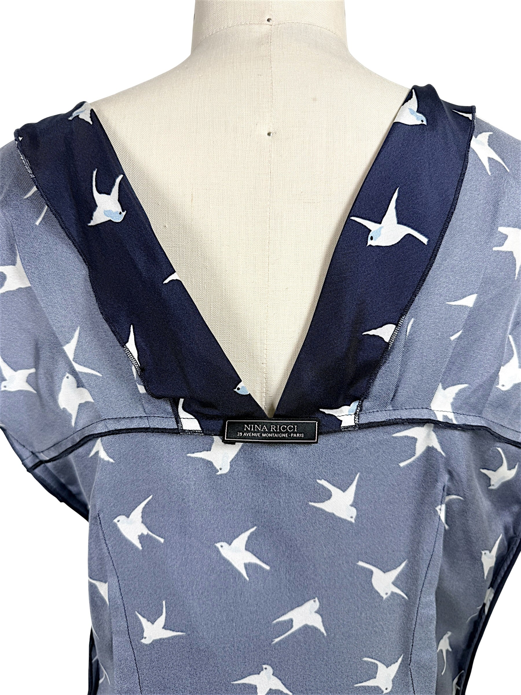 Interior Nina Ricci designer label shown on open back navy silk swallow print dress.