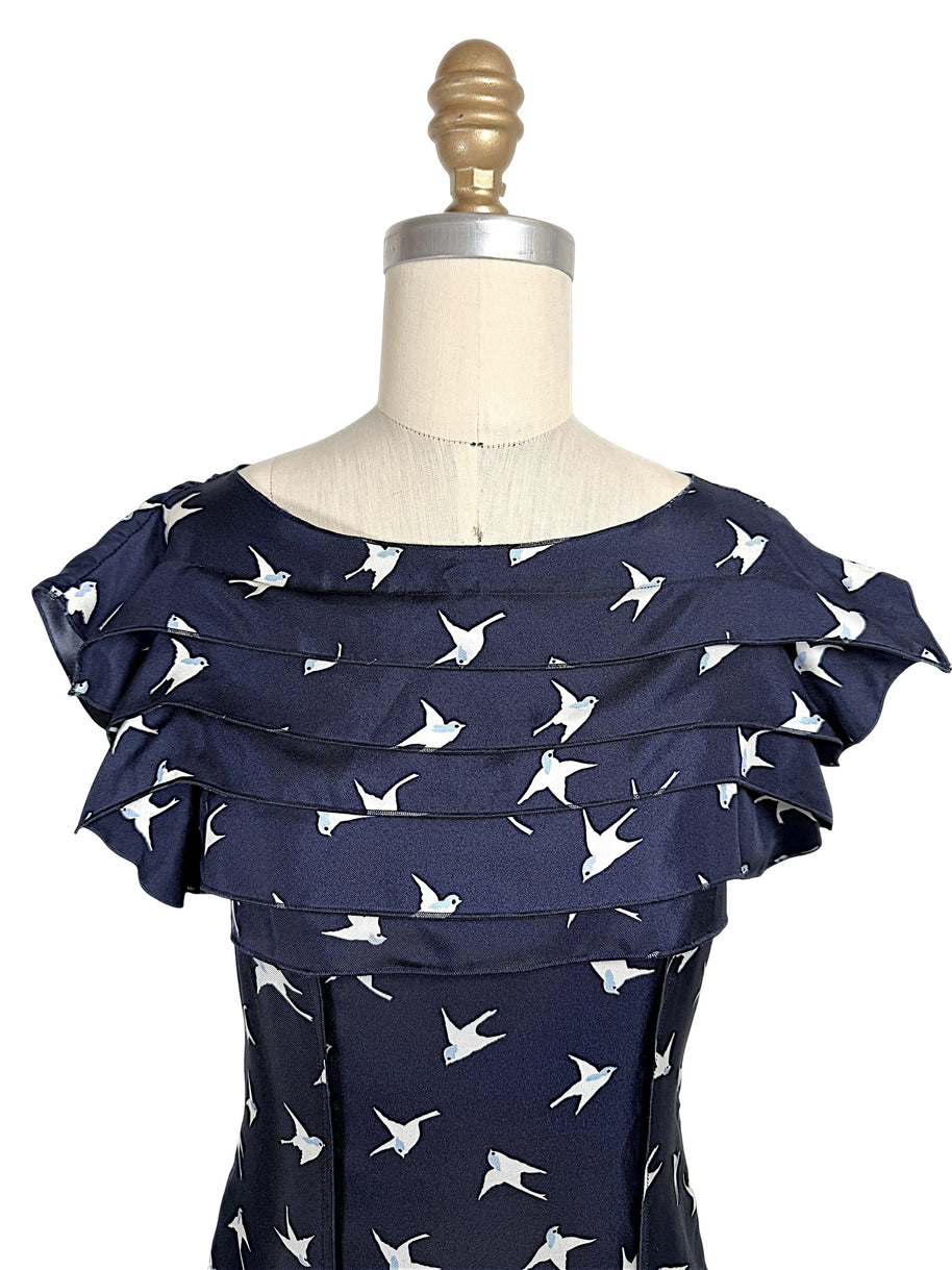 Close-up of layered ruffle neckline and ivory swallow bird motif on Nina Ricci navy silk dress.