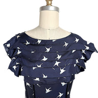 Close-up of layered ruffle neckline and ivory swallow bird motif on Nina Ricci navy silk dress.