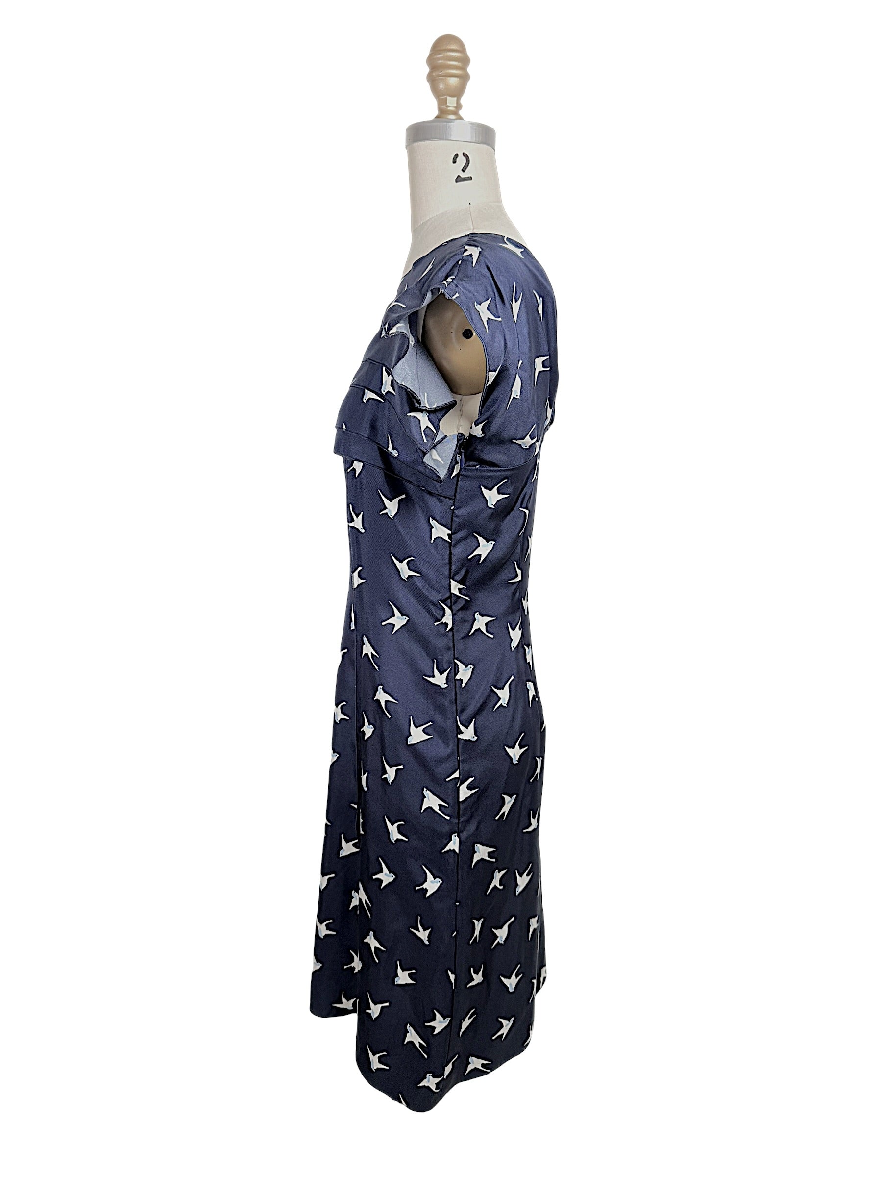 Side profile of Nina Ricci navy silk swallow print dress featuring layered ruffle neckline and fitted silhouette.