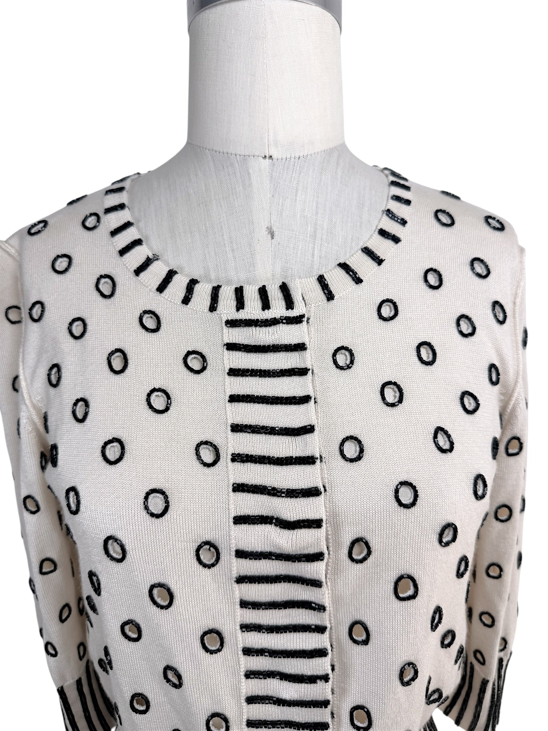 Close-up detail of Oscar de la Renta ivory sweater featuring black beaded polka dot embellishment and striped trim neckline