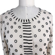 Close-up detail of Oscar de la Renta ivory sweater featuring black beaded polka dot embellishment and striped trim neckline