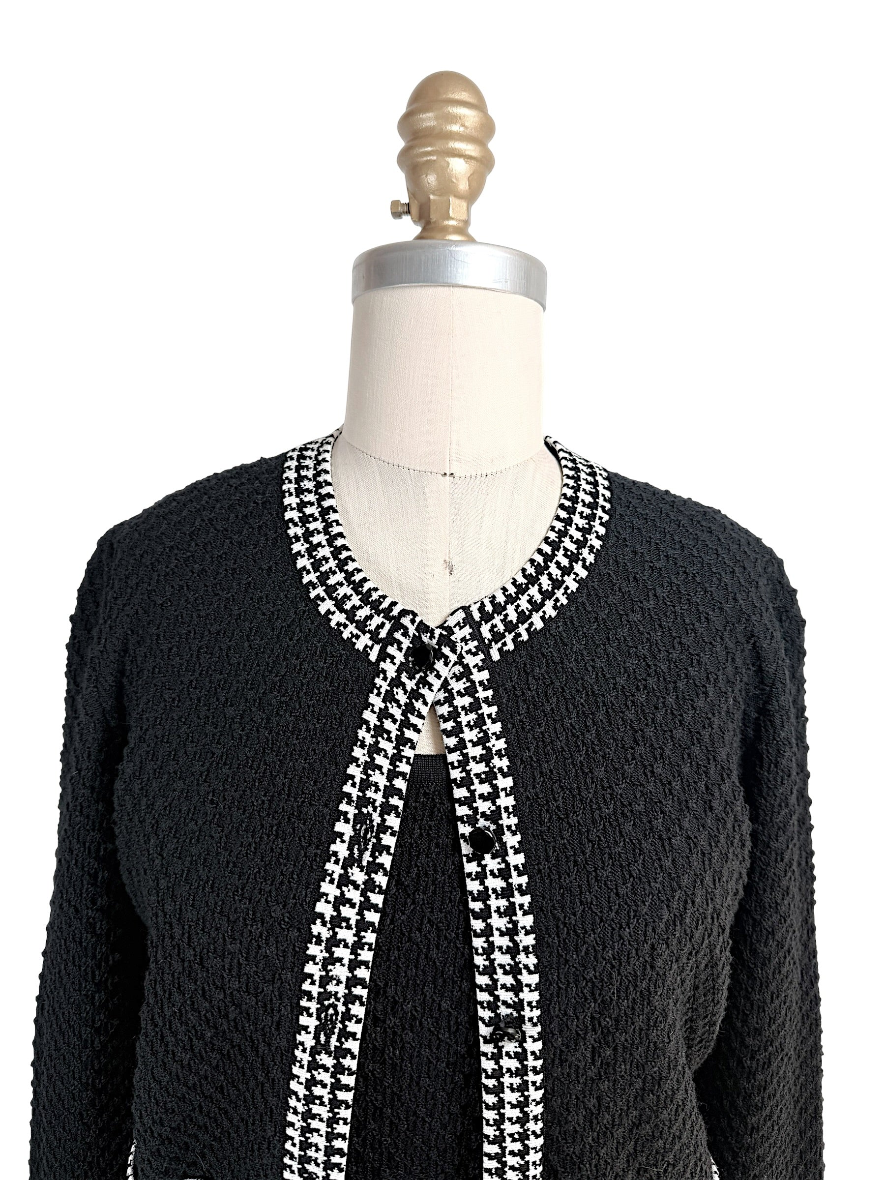 Close-up front detail of Oscar de la Renta textured knit cardigan with houndstooth trim neckline and button closure
