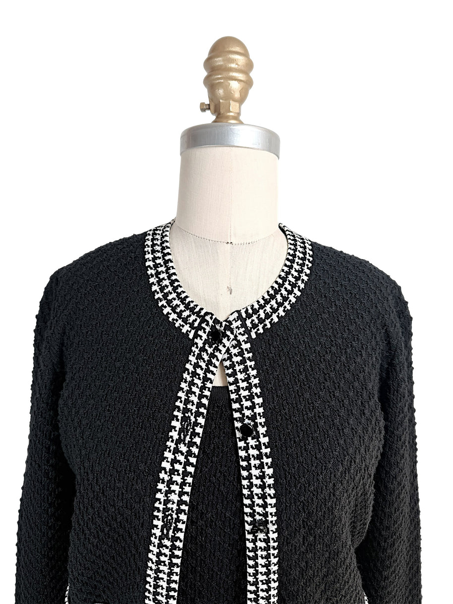 Close-up front detail of Oscar de la Renta textured knit cardigan with houndstooth trim neckline and button closure