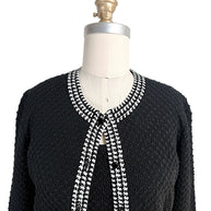 Close-up front detail of Oscar de la Renta textured knit cardigan with houndstooth trim neckline and button closure