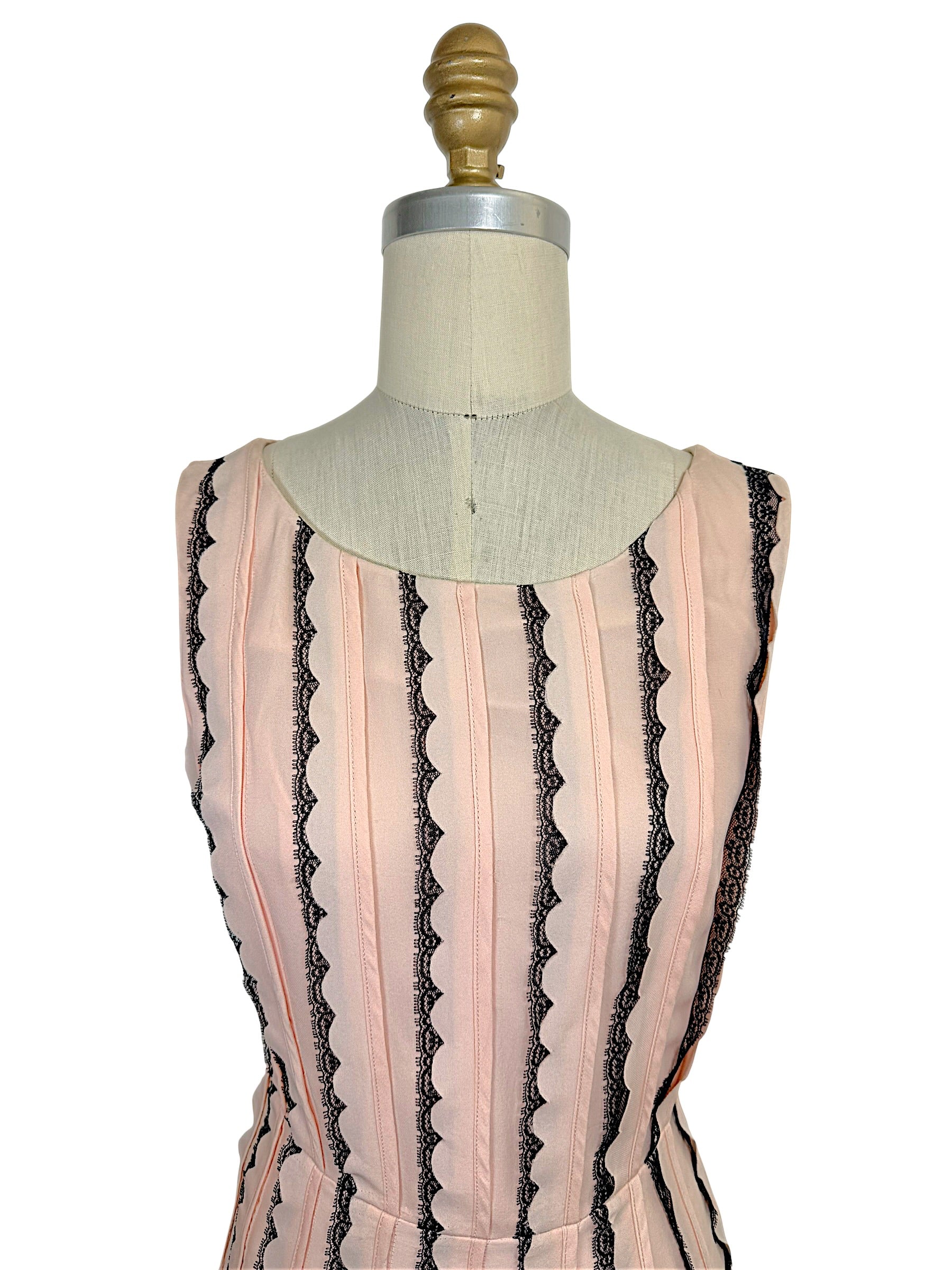 Close-up of the Oscar de la Renta Resort 2014 blush pink dress highlighting the rounded neckline, tailored bodice, and vertical black lace stripe detailing.