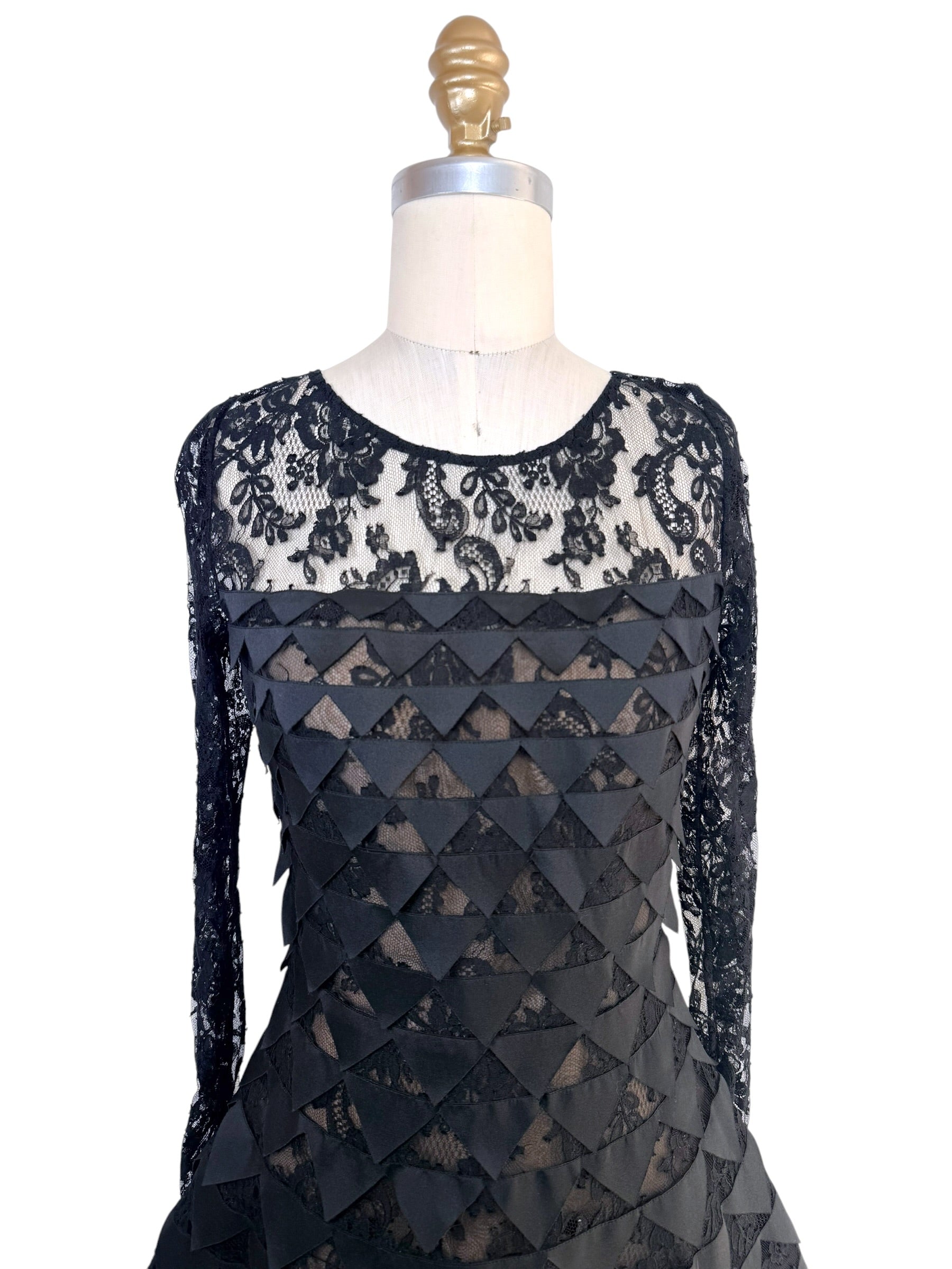Front upper detail of Oscar de la Renta Resort 2018 black lace dress with illusion neckline and layered geometric appliqué