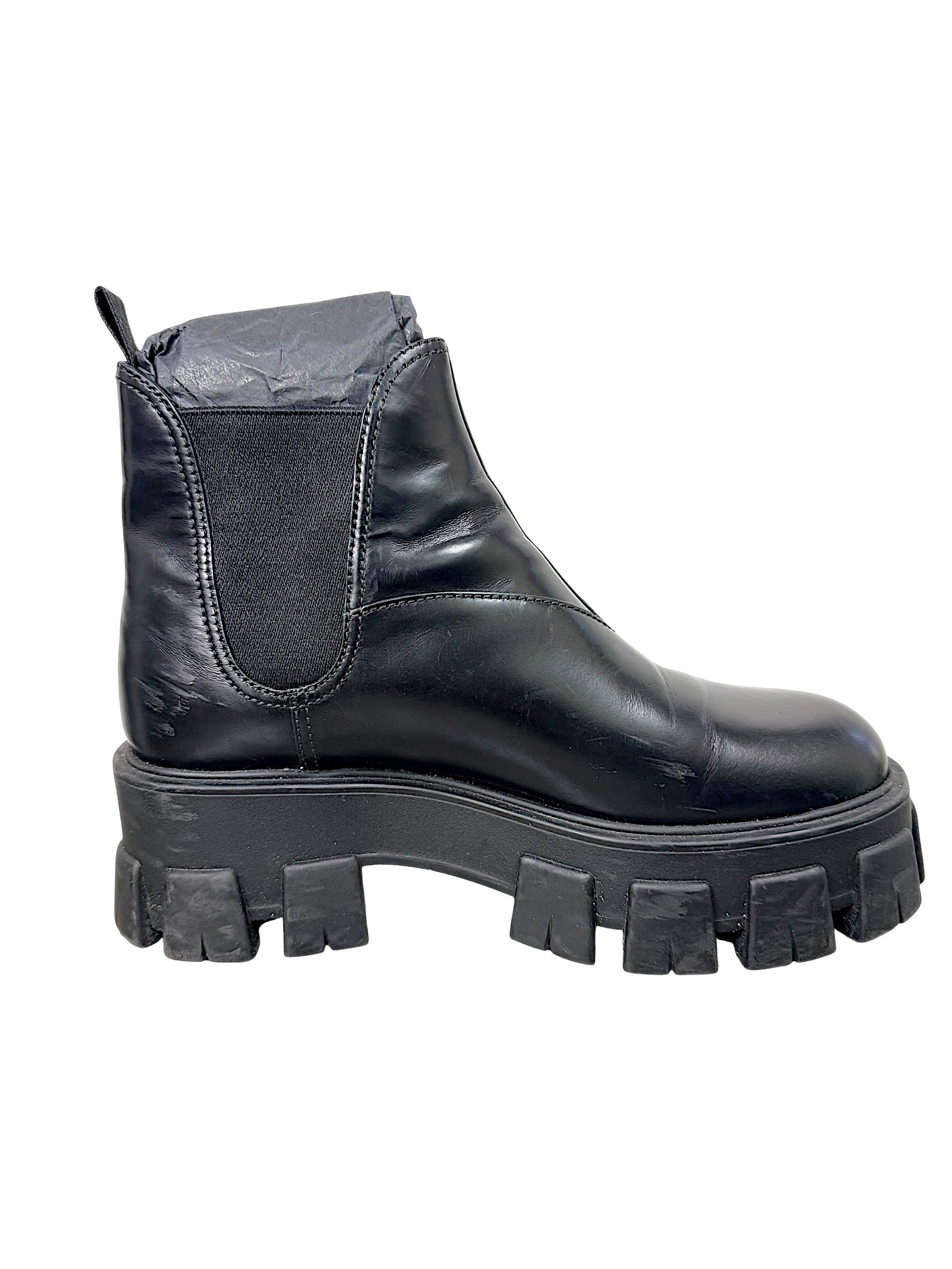 Side view of Prada Monolith Chelsea boot showing black leather upper, elastic panel and oversized rubber sole