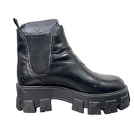 Side view of Prada Monolith Chelsea boot showing black leather upper, elastic panel and oversized rubber sole