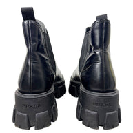 Rear view of Prada Monolith black leather Chelsea boots showing Prada logo embossed on chunky heels