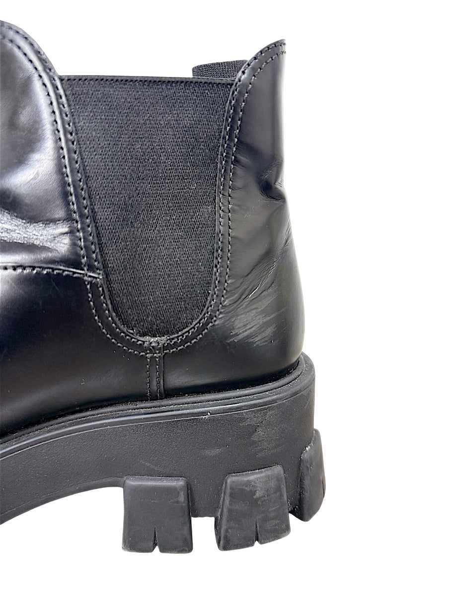Close-up of Prada Monolith black leather Chelsea boot showing scuffing and wear near heel and elastic side gusset