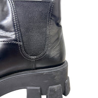 Close-up of Prada Monolith black leather Chelsea boot showing scuffing and wear near heel and elastic side gusset