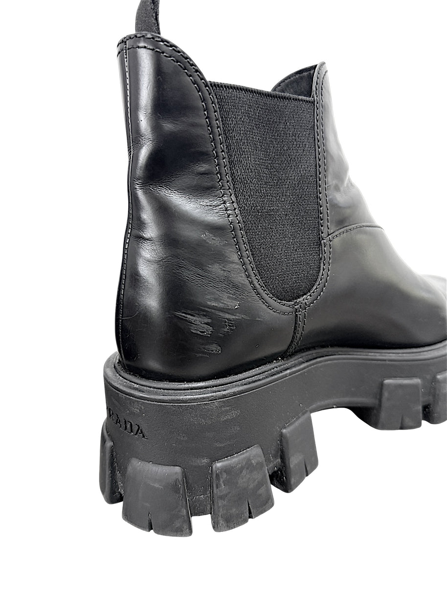 Close-up of Prada Monolith Chelsea boot showing scuffing to black leather at rear heel and wear to chunky rubber sole