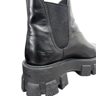 Close-up of Prada Monolith Chelsea boot showing scuffing to black leather at rear heel and wear to chunky rubber sole