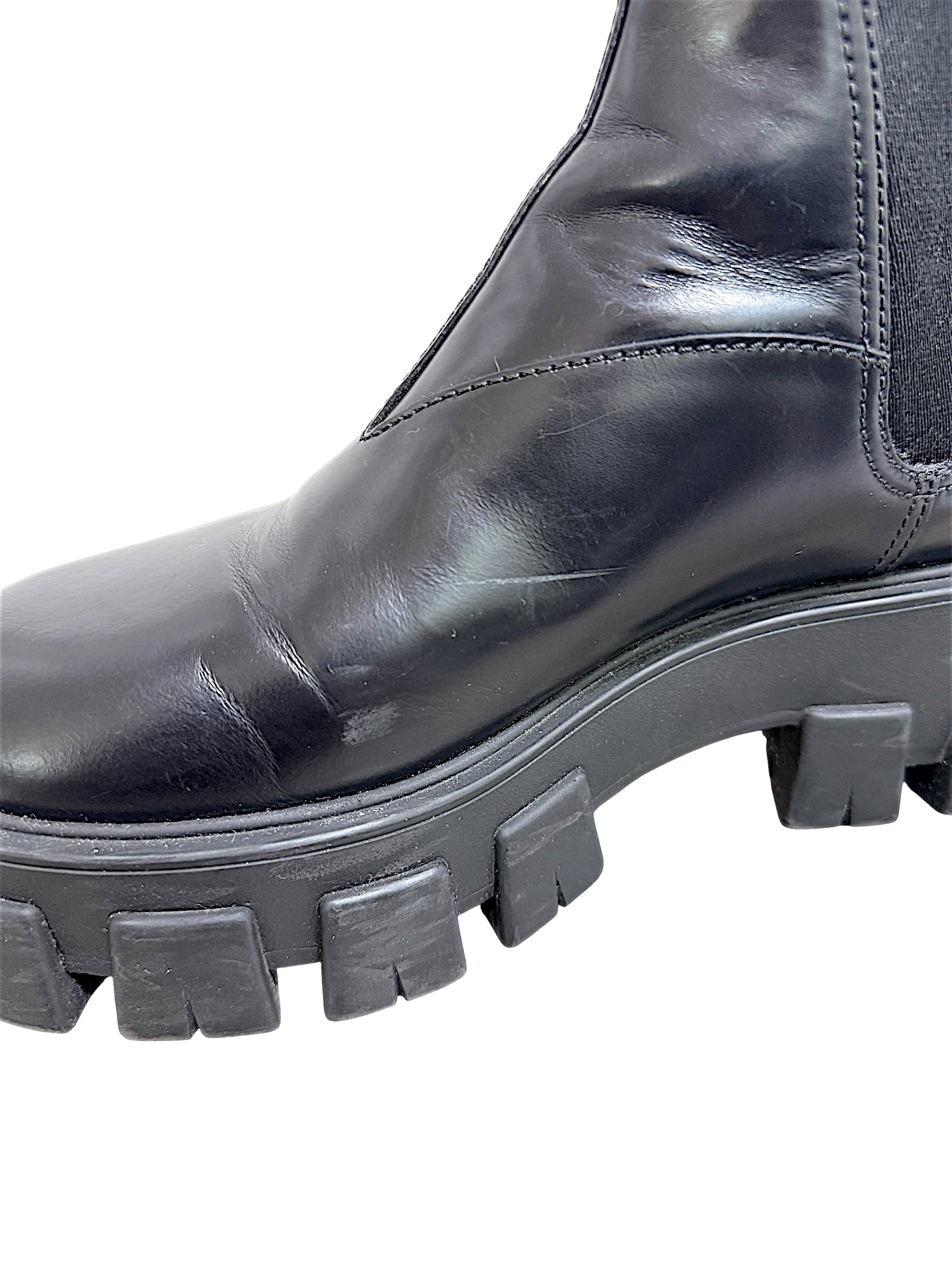 Close-up of Prada Monolith Chelsea boot showing surface scuffs and creasing on black leather upper and lug sole