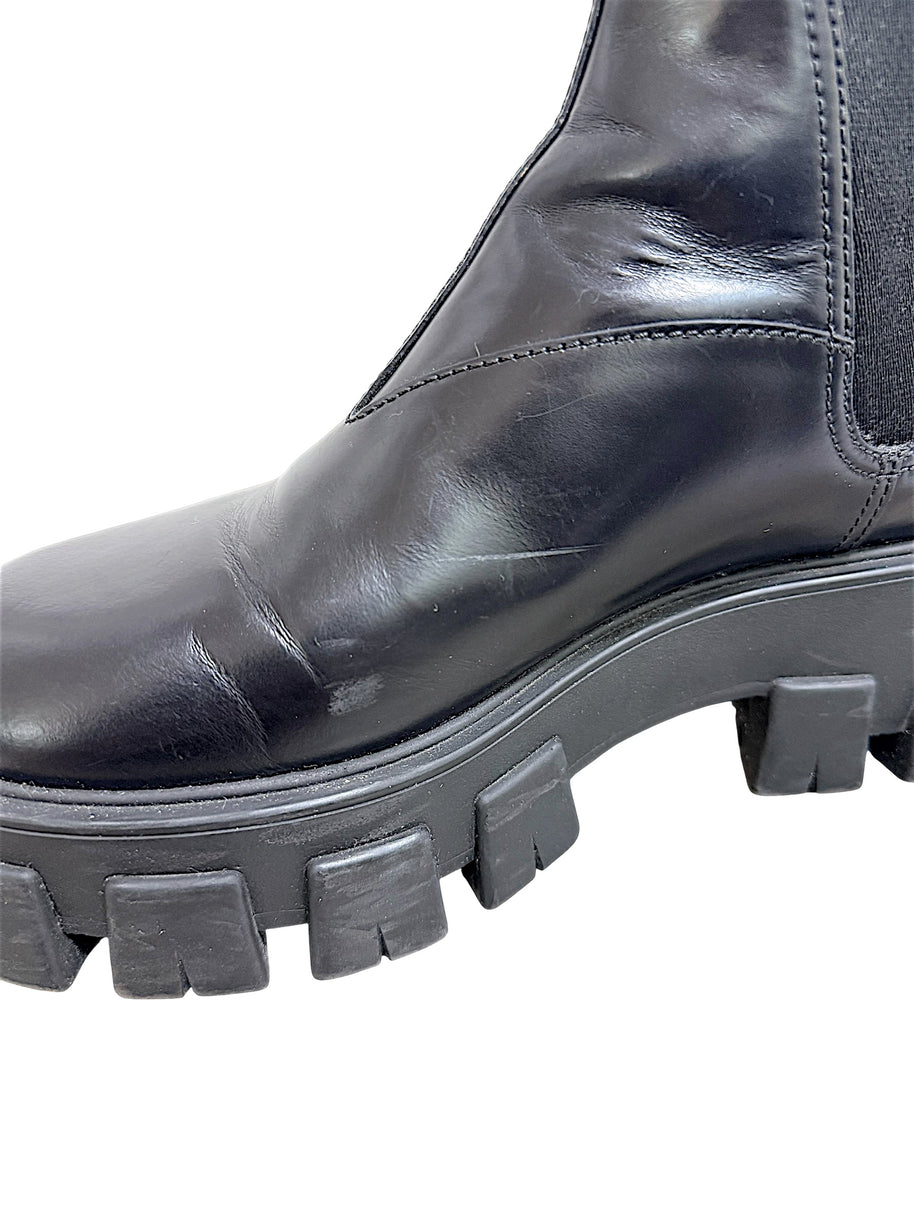 Close-up of Prada Monolith Chelsea boot showing surface scuffs and creasing on black leather upper and lug sole