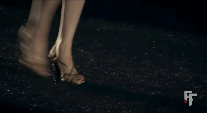 10-second archival runway video of Chanel Pre-Fall 2010 Paris-Shanghai Métiers d'Art Collection Look 42, showing Karl Lagerfeld's ivory bouclé skirt suit with signature navy and crimson braided trim as presented on the Shanghai runway. Included as a historical runway reference for the documented ensemble.