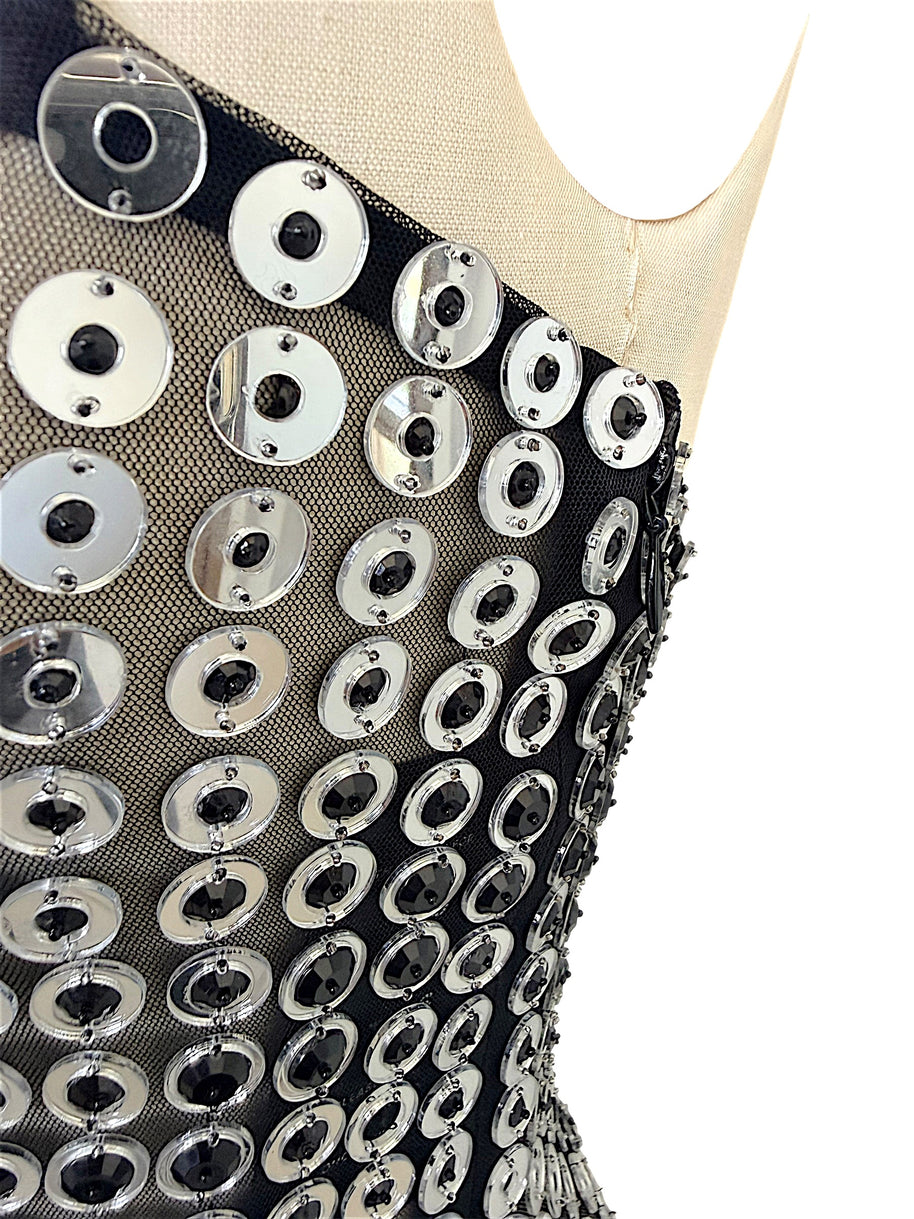 Close-up of Retrofête Maddy dress showing reflective silver circular discs with black faceted centers on sheer mesh