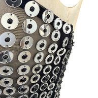 Close-up of Retrofête Maddy dress showing reflective silver circular discs with black faceted centers on sheer mesh