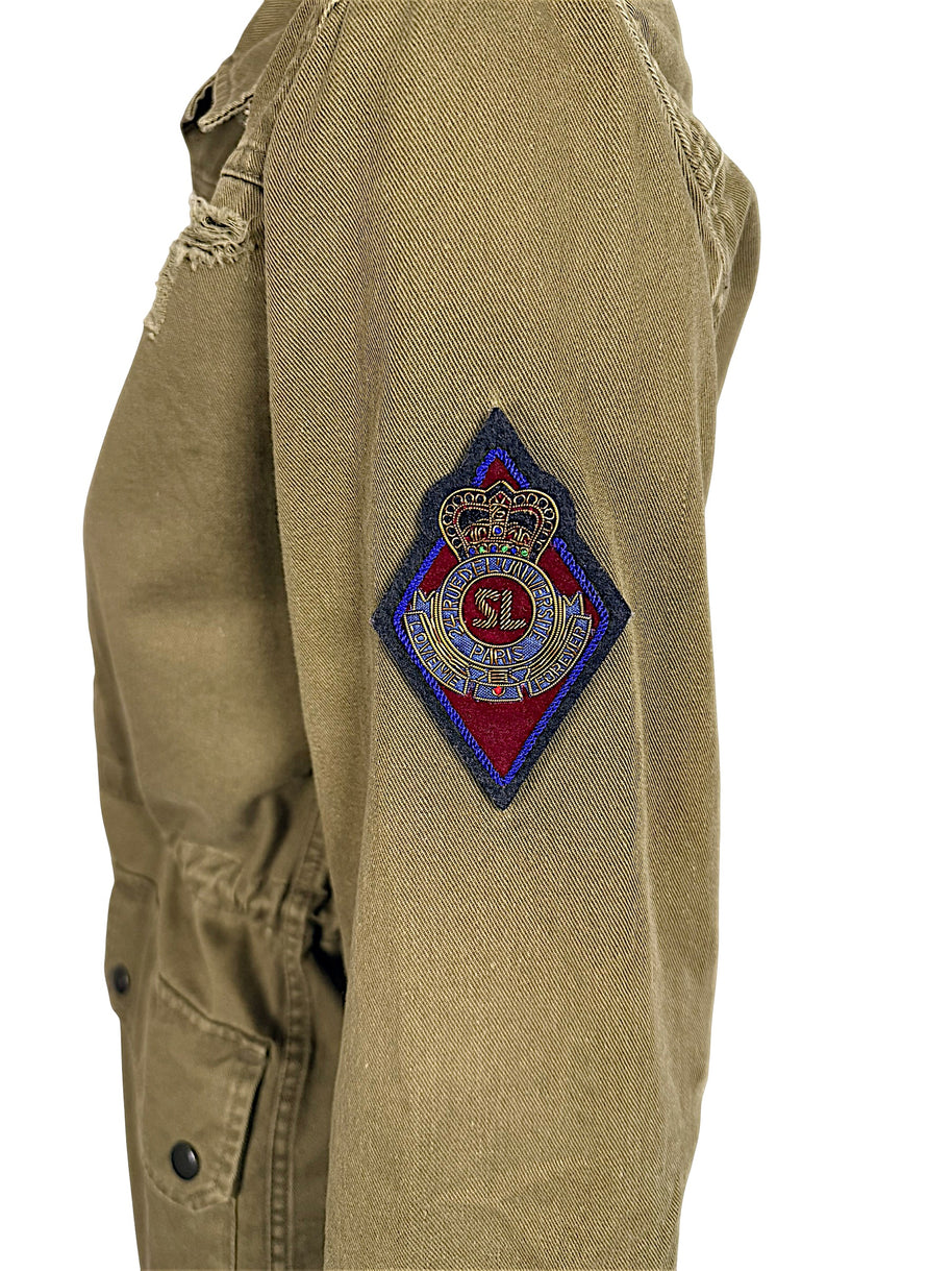 Close-up of Saint Laurent Paris olive green military jacket featuring multicolor embroidered SL crowned crest patch on upper sleeve.
