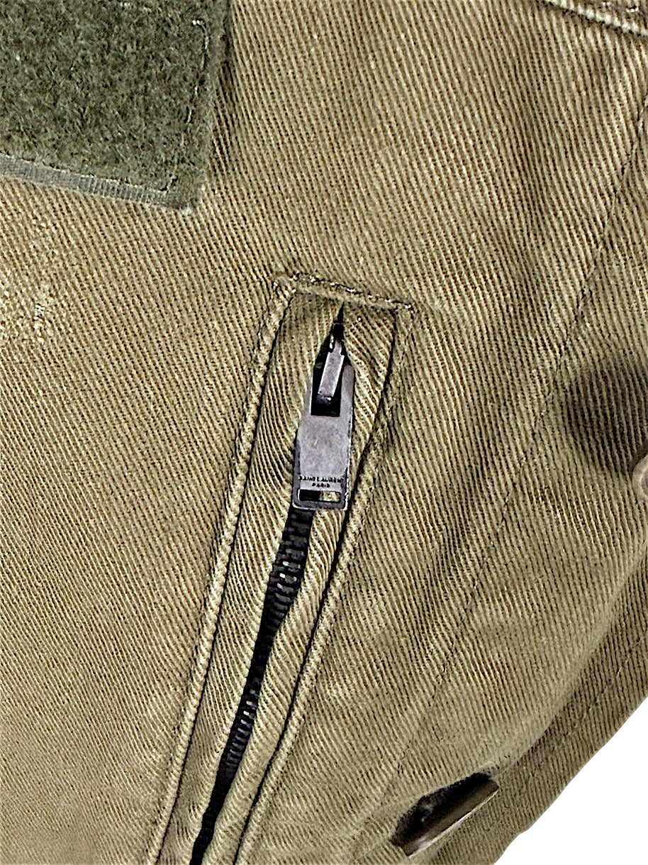Close-up of Saint Laurent Paris engraved zipper pull on olive green cotton twill military jacket with distressed finish