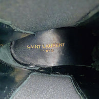 Interior of Saint Laurent Paris black leather Chelsea ankle boot showing gold Saint Laurent Paris designer logo stamped on the black leather insole.