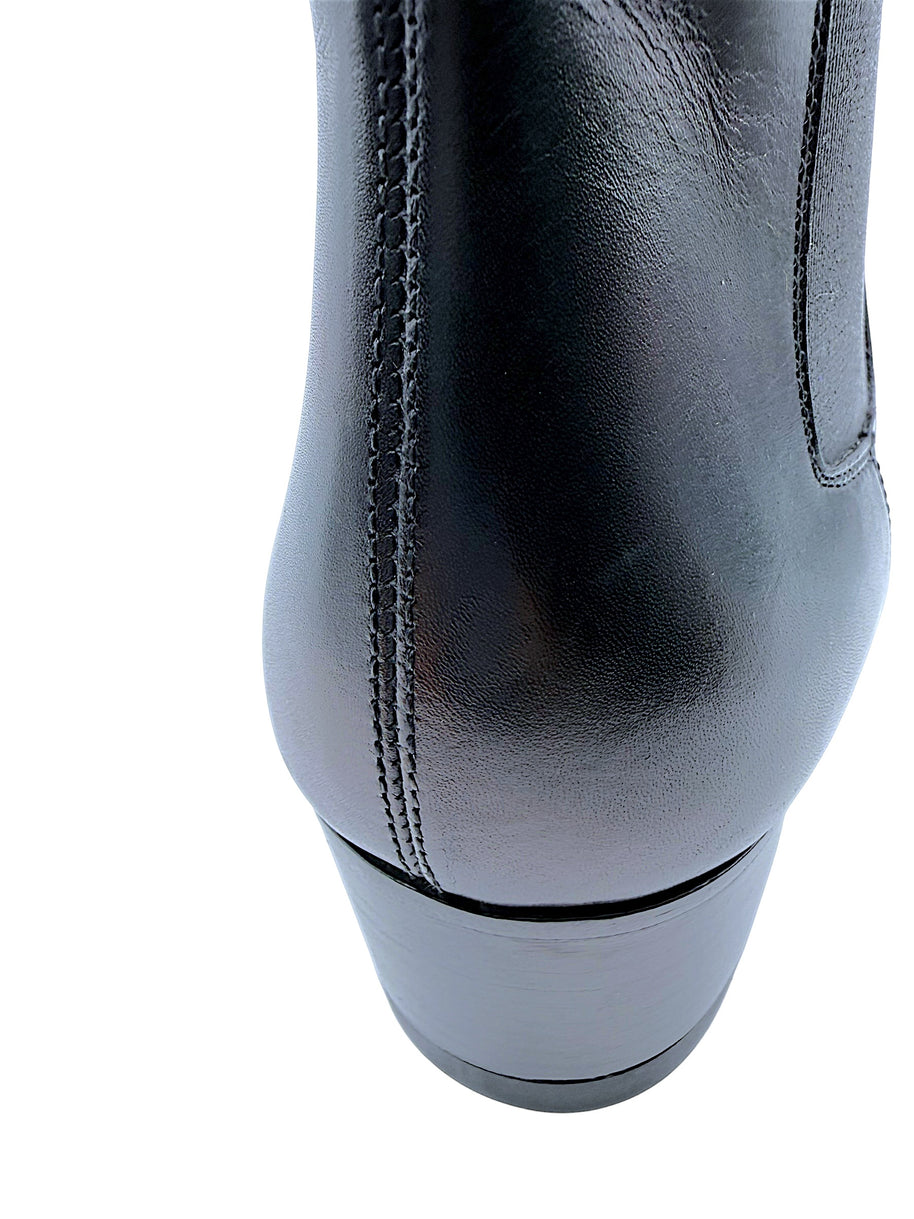Close-up rear view of Saint Laurent Paris black leather Chelsea ankle boot showing light scuff on smooth leather heel counter, vertical stitched seam and low stacked block heel.