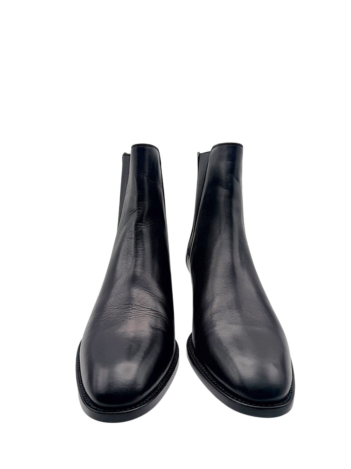 Front view of Saint Laurent Paris black leather Chelsea ankle boots showing sleek almond-shaped toes and natural leather creasing.