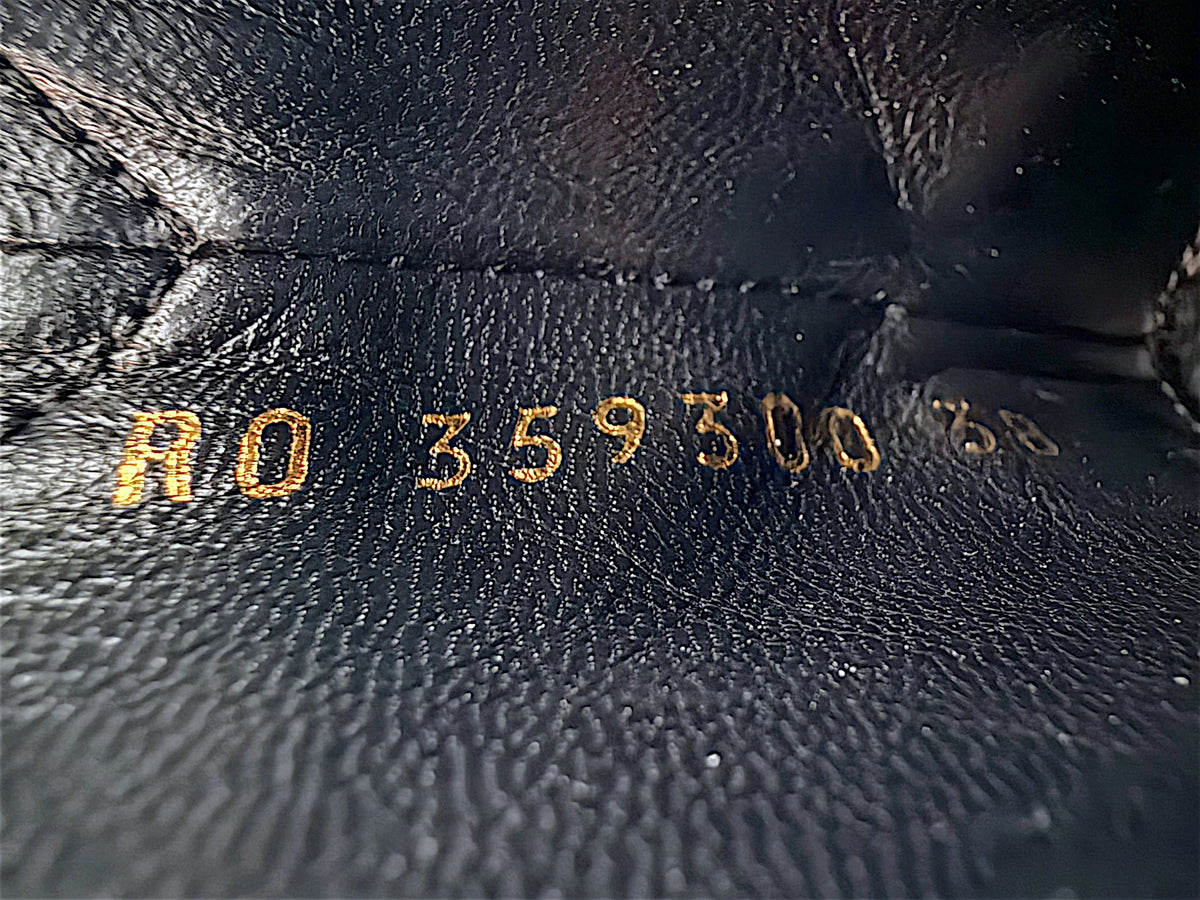 Close-up of gold stamped Saint Laurent Paris footwear reference code inside black leather Chelsea ankle boot, showing interior leather texture and identification markings.