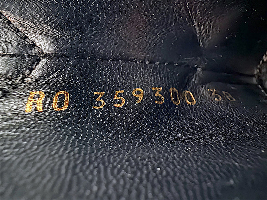 Close-up of gold stamped Saint Laurent Paris footwear reference code inside black leather Chelsea ankle boot, showing interior leather texture and identification markings.