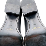 Detailed view of Saint Laurent Paris black leather Chelsea boot soles showing gold designer logos, Made in Italy stamps, European size 38 and surface wear on stacked heels and leather outsoles.