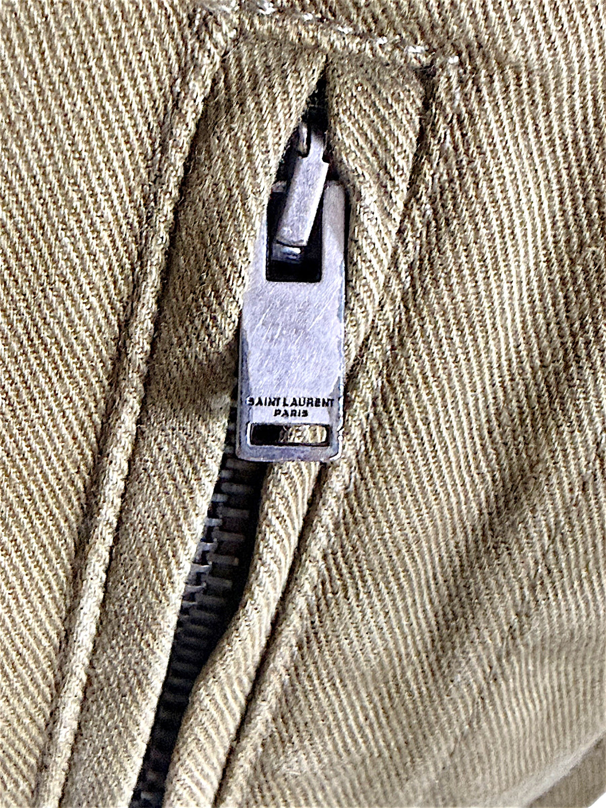 Detailed view of Saint Laurent Paris branded metal zipper and stitching on Fall 2018 olive green military utility jacket