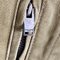 Detailed view of Saint Laurent Paris branded metal zipper and stitching on Fall 2018 olive green military utility jacket