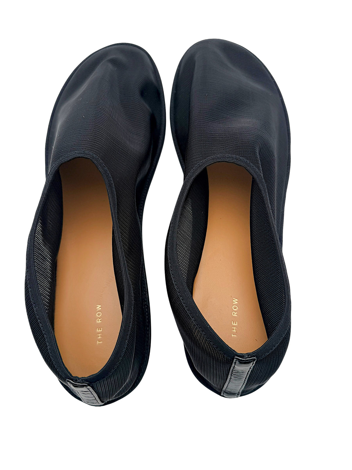 Top interior view of The Row black mesh sock ballet flats featuring tan leather insoles, gold-tone The Row branding and black heel tabs.