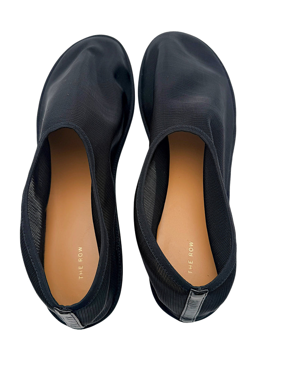 Top interior view of The Row black mesh sock ballet flats featuring tan leather insoles, gold-tone The Row branding and black heel tabs.