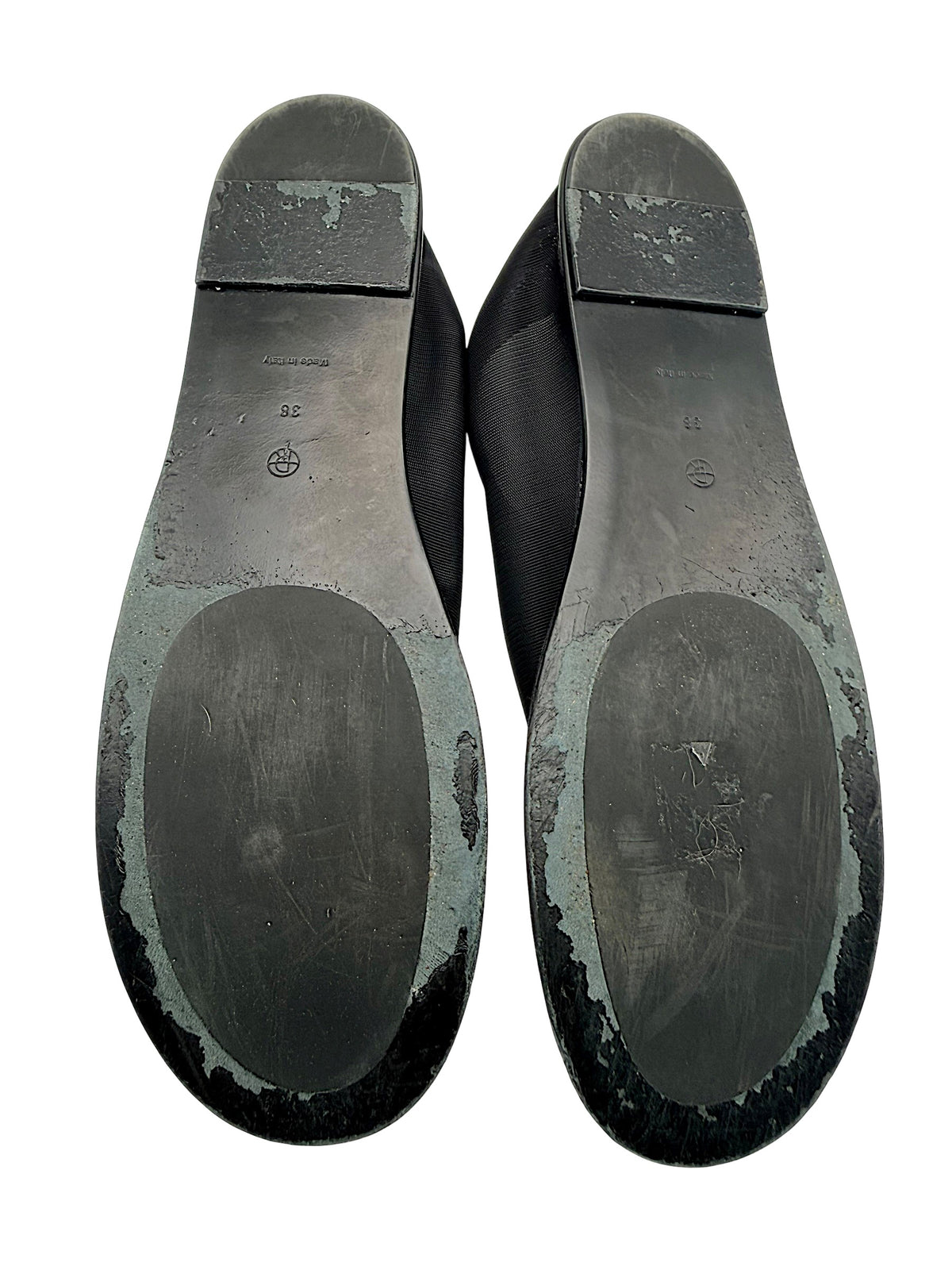 Bottom view of The Row black mesh sock flats, EU size 38, showing both outsoles with visible surface wear, scuffing and peeling finish around the edges and heels.