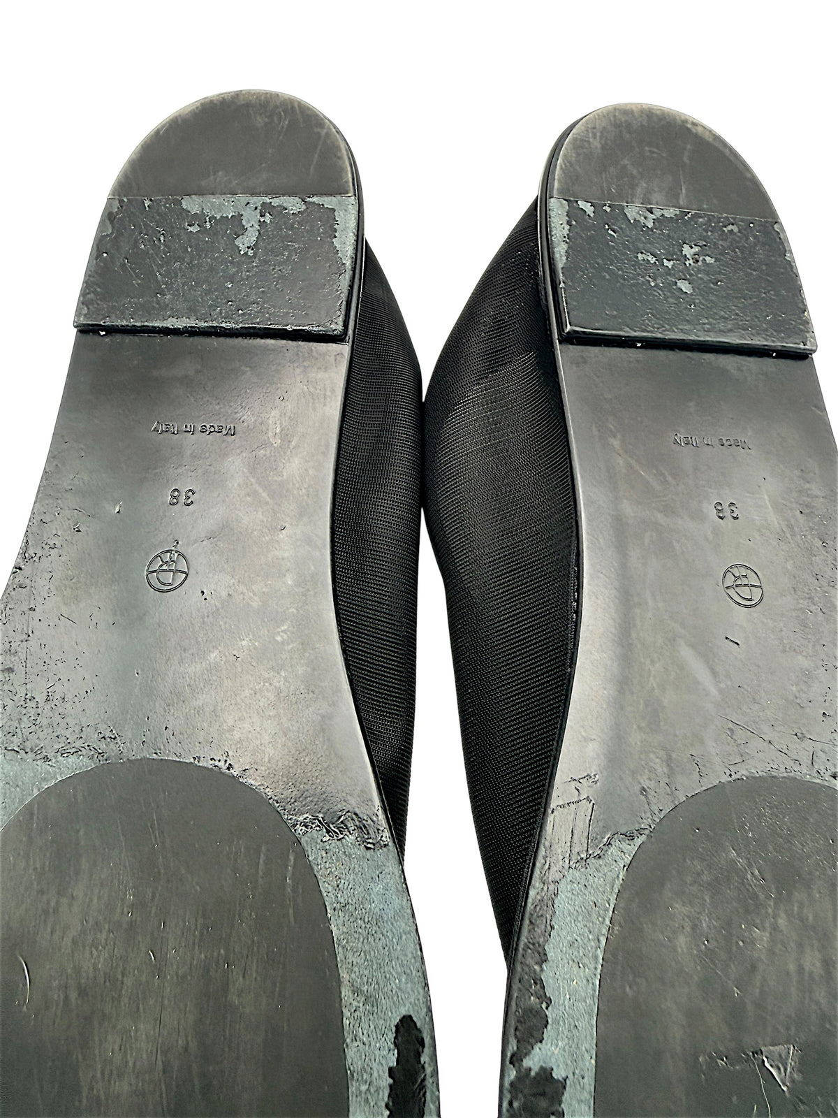 Close-up of The Row black mesh sock flats showing size 38 markings, Made in Italy stamps, scuffed heel blocks and worn outsole finish with visible peeling.