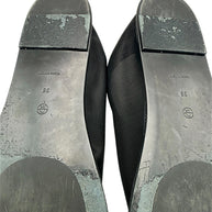 Close-up of The Row black mesh sock flats showing size 38 markings, Made in Italy stamps, scuffed heel blocks and worn outsole finish with visible peeling.