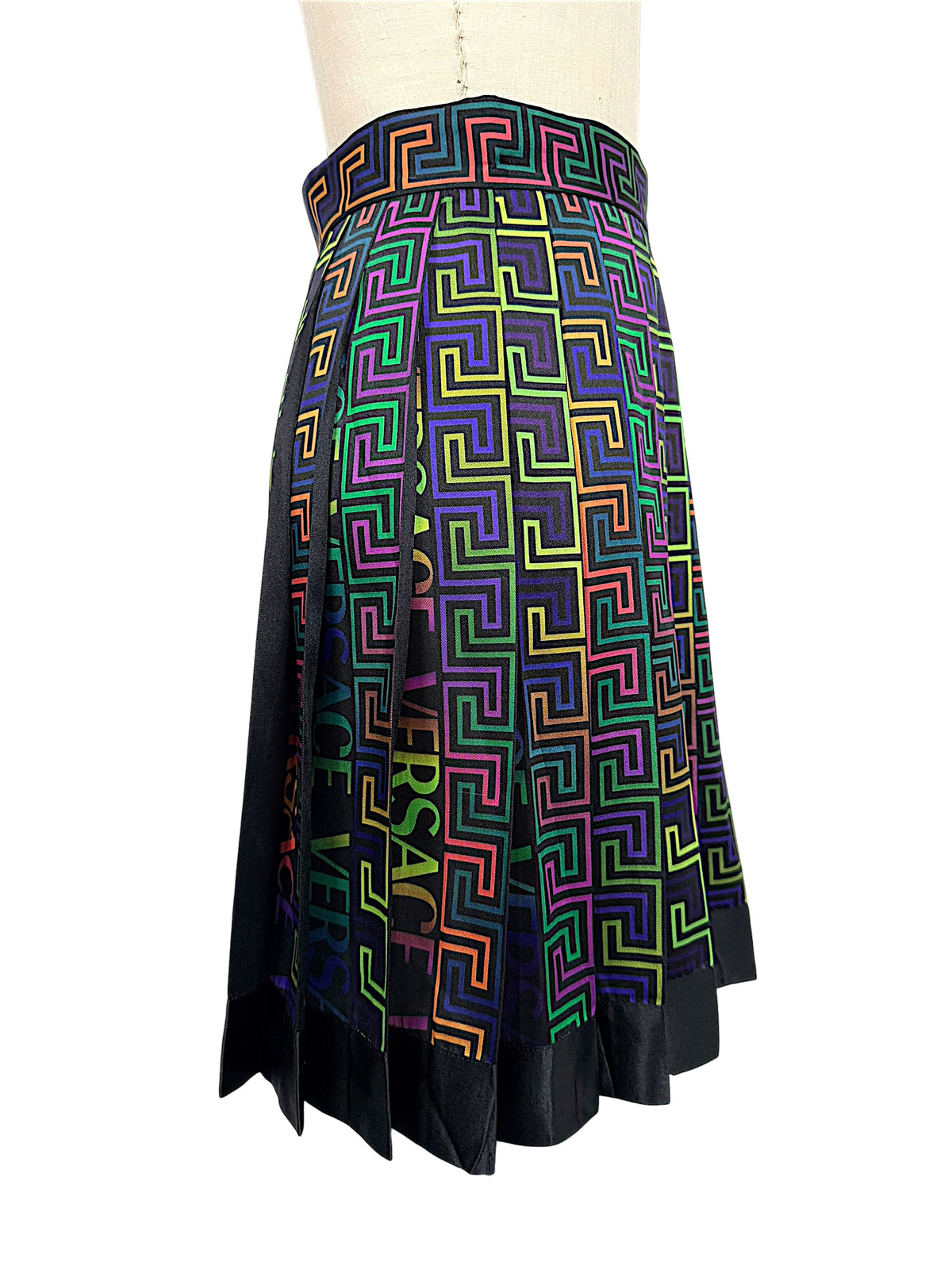 Side profile of Versace FW 2021 multicolor La Greca pleated skirt highlighting its high waistband, flared silhouette and colorful Greek Key motif.