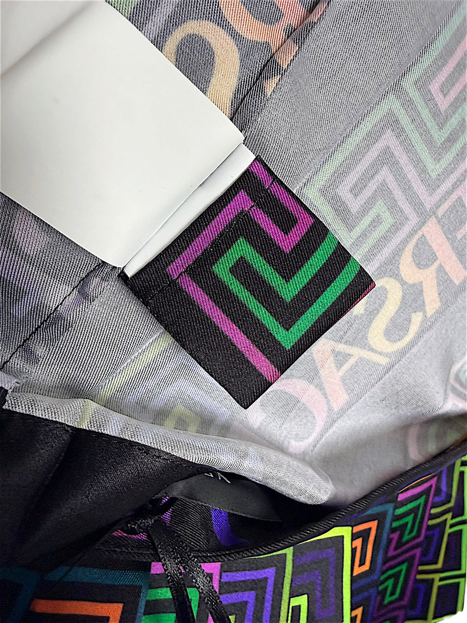 Interior detail of Versace Fall Winter 2021 La Greca pleated skirt showing pink and green Greek Key woven label, fabric lining and multicolor geometric print.